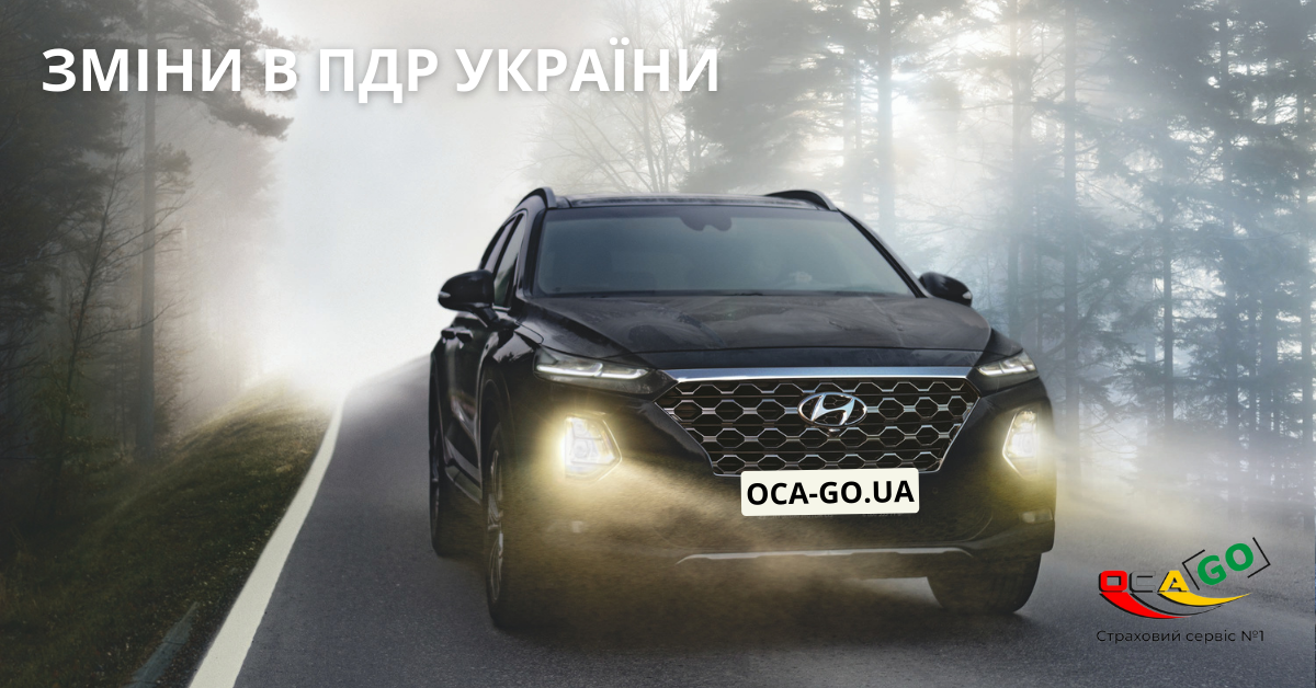 Чорний позашляховик на трасі поза містом з увімкнутими фарами.