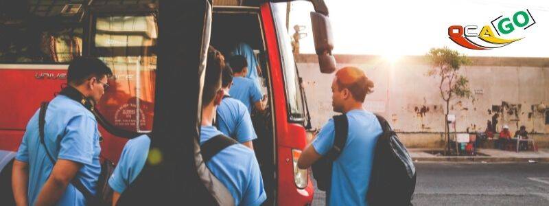 Группа людей садится в красный автобус